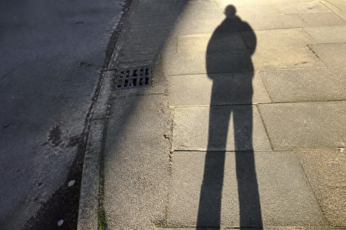 A shadow stretched across sunlit pavement